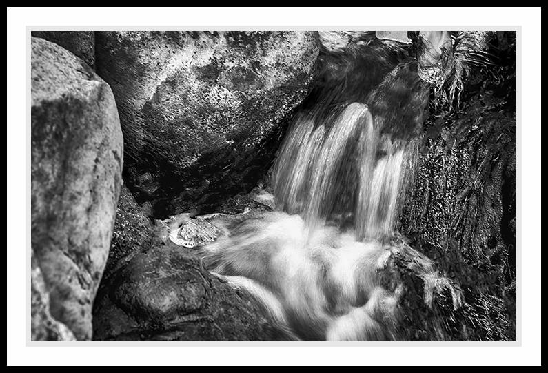 Water casading into a small pool in black and white.